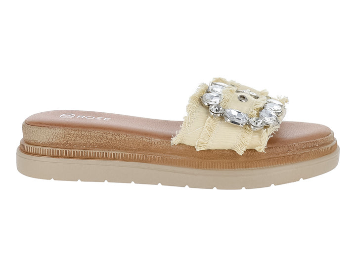 Sandalia deslizable color beige con correa de tela deshilachada y hebilla decorativa con brillantes.