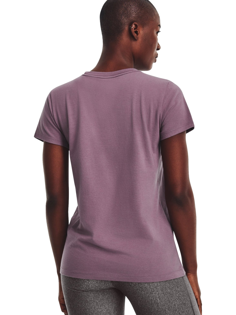 Mujer vistiendo camiseta deportiva morada de manga corta con logo blanco de Under Armour y shorts grises.