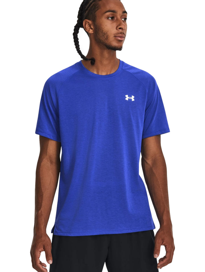 Hombre vistiendo una camiseta deportiva azul de manga corta Under Armour con logo blanco.