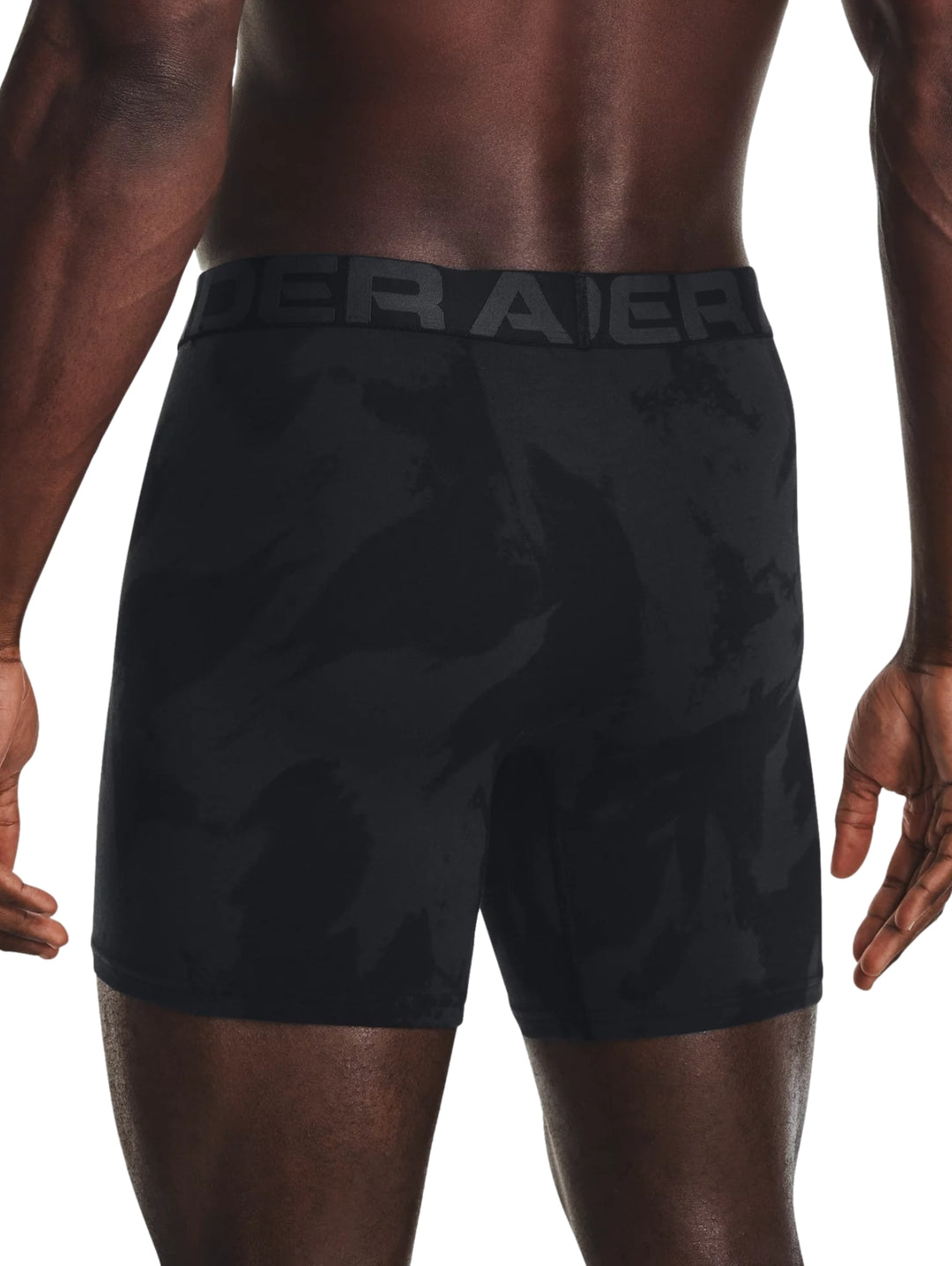 Hombre vistiendo bóxers deportivos Under Armour en color negro con patrón de camuflaje oscuro.