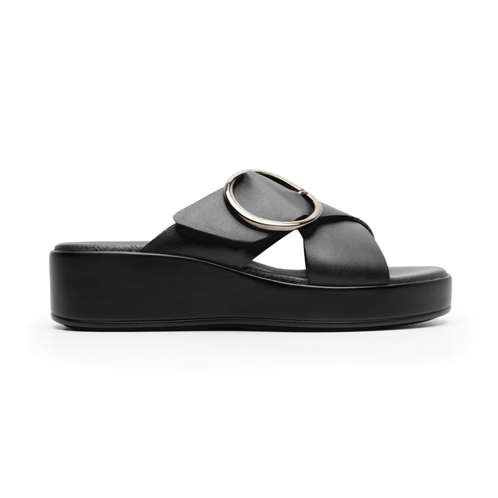 Sandalia de plataforma color negro con una hebilla circular metálica en la parte superior.