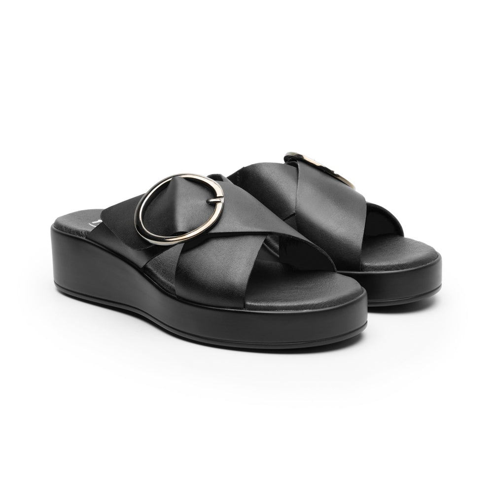 Sandalia de plataforma color negro con una hebilla circular metálica en la parte superior.