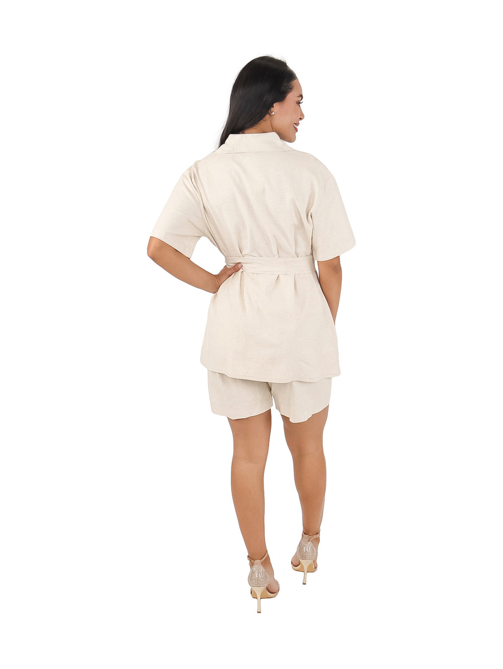 Mujer vistiendo conjunto de lino color arena compuesto por camisa con cinturón y short.