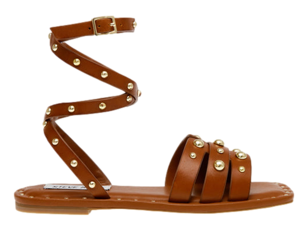 Sandalia plana color cognac de Steve Madden con tiras envolventes al tobillo y detalles de tachuelas doradas.