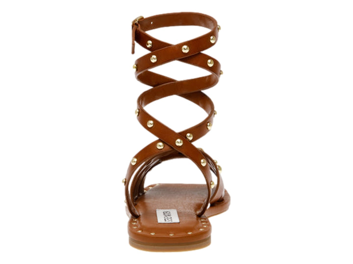 Sandalia plana color cognac de Steve Madden con tiras envolventes al tobillo y detalles de tachuelas doradas.
