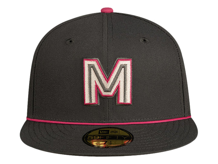 Gorra de béisbol New Era color gris oscuro con detalles en rosa y letra M bordada al frente.
