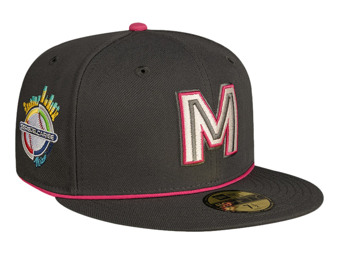 Gorra de béisbol New Era color gris oscuro con detalles en rosa y letra M bordada al frente.
