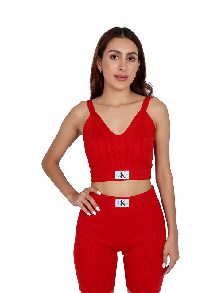 Mujer vistiendo un bralette tejido color rojo intenso de Calvin Klein con etiqueta blanca.