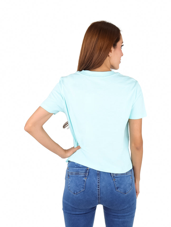 Mujer vistiendo camiseta azul claro de manga corta Calvin Klein y jeans azules.