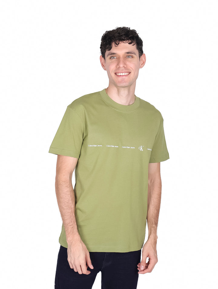 Hombre vistiendo una camiseta de manga corta color verde oscuro con logo repetido de Calvin Klein en el pecho.