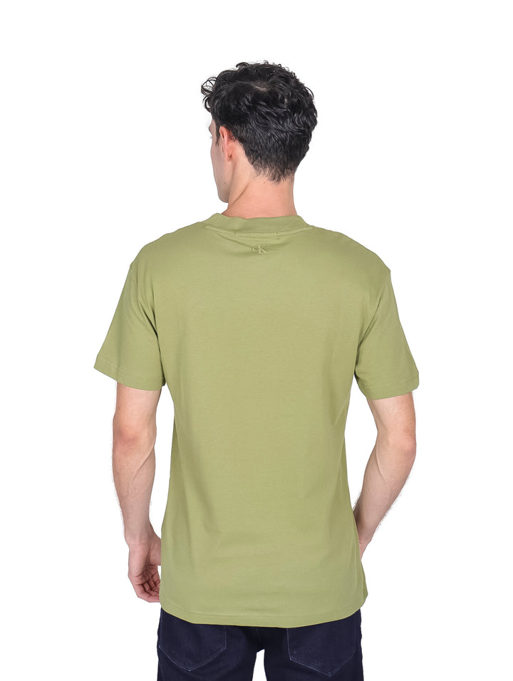 Hombre vistiendo una camiseta de manga corta color verde oscuro con logo repetido de Calvin Klein en el pecho.