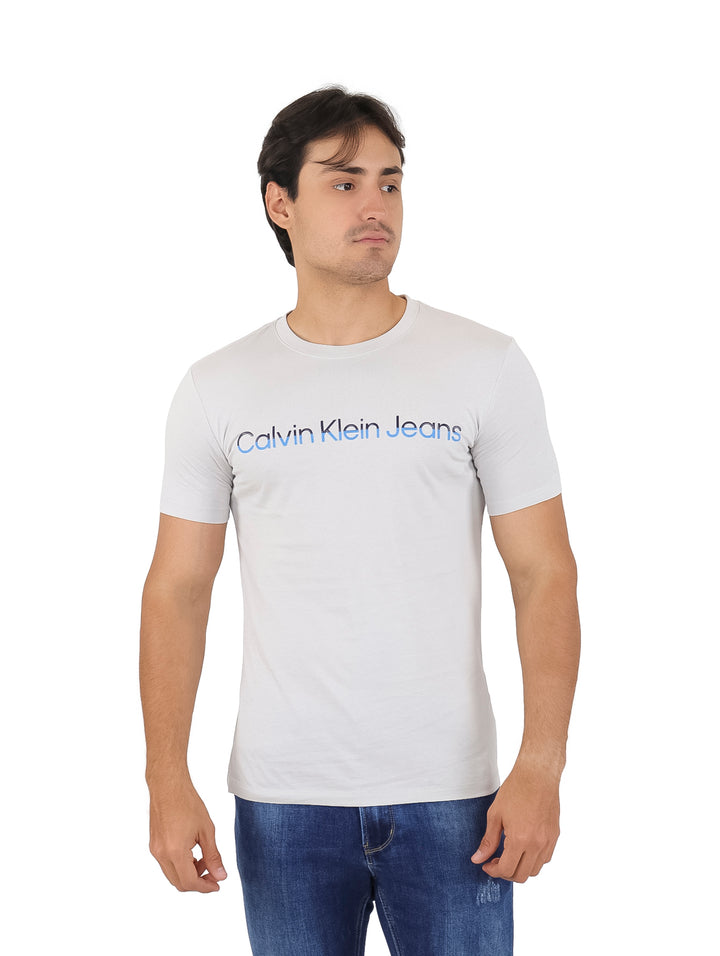 Hombre vistiendo una camiseta de manga corta color gris claro con logotipo de Calvin Klein Jeans en el pecho.