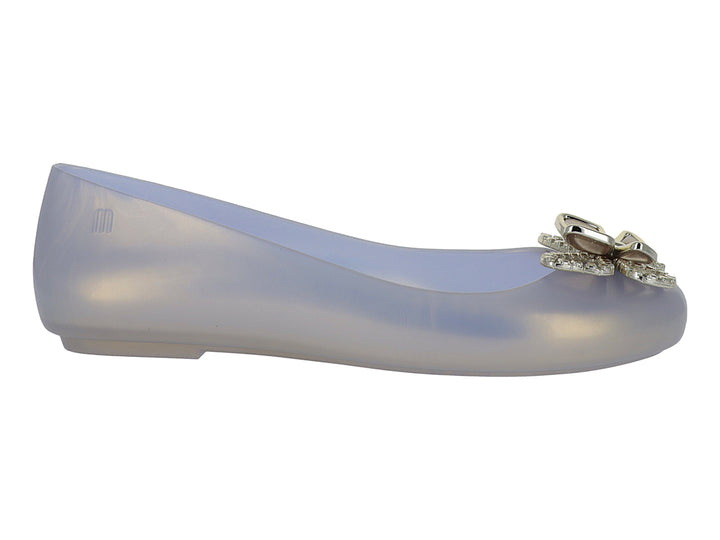 Zapato plano Melissa color blanco translúcido con adorno brillante en la punta.