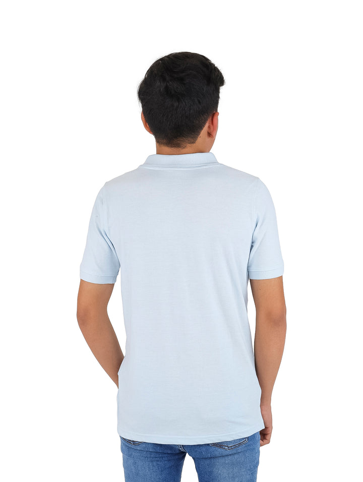 Niño vistiendo una playera polo de color azul cielo y pantalones de mezclilla.