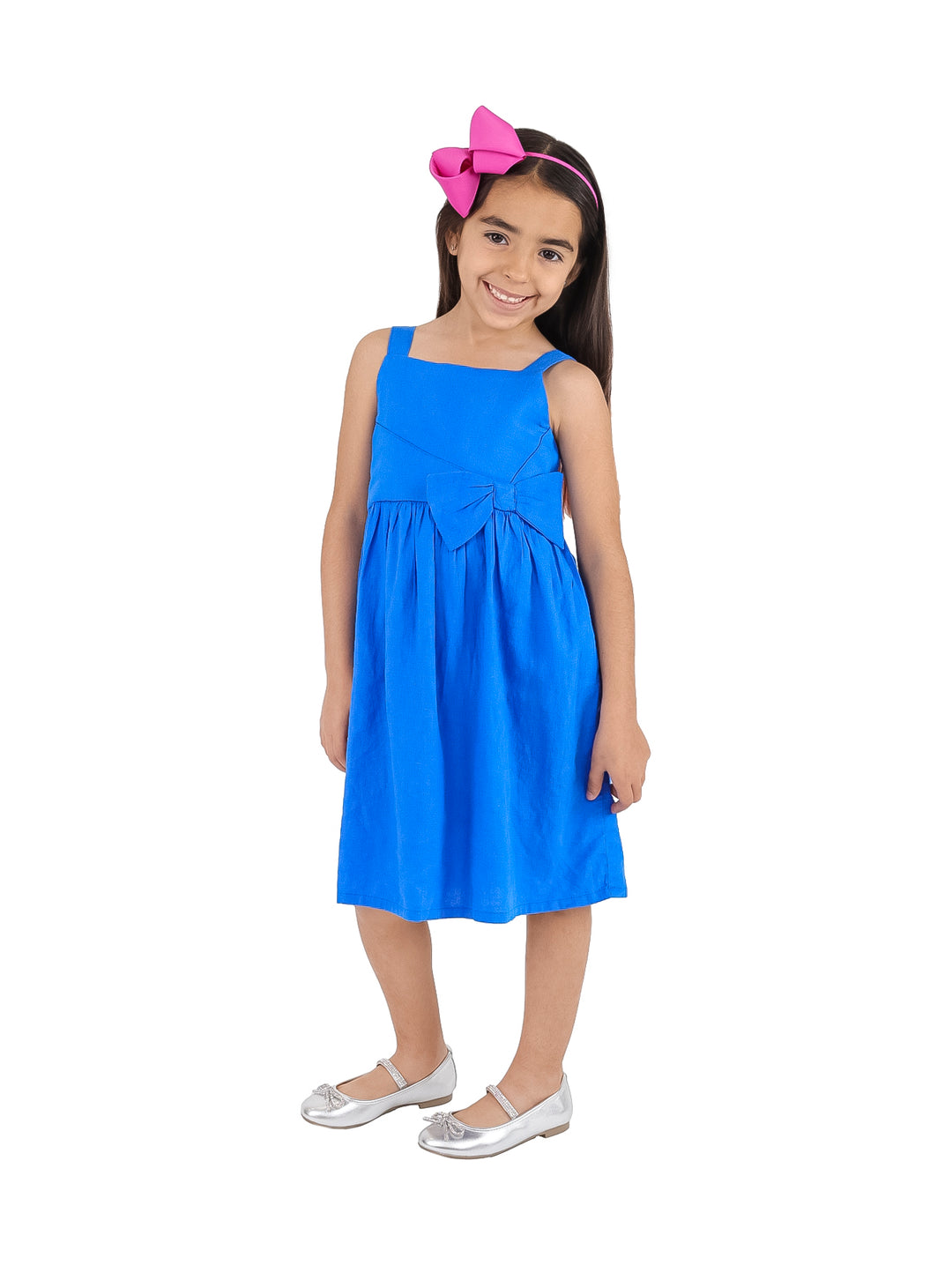 Niña con vestido azul corto sin mangas, moño en la cintura y diadema rosa.
