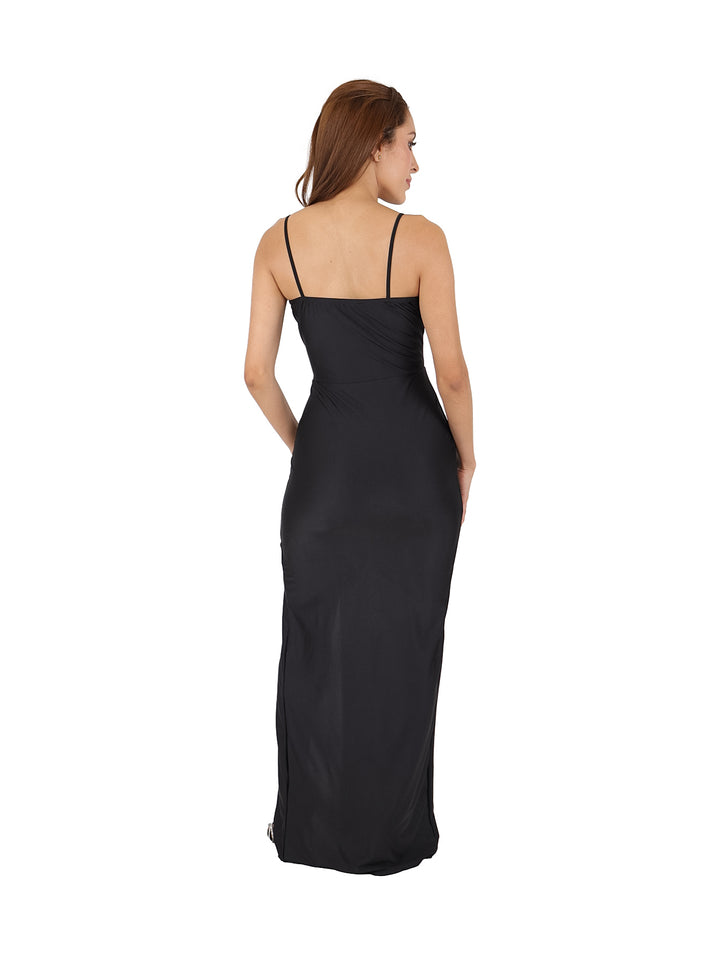 Mujer vistiendo un vestido largo negro ajustado con tirantes finos y abertura lateral en la pierna.