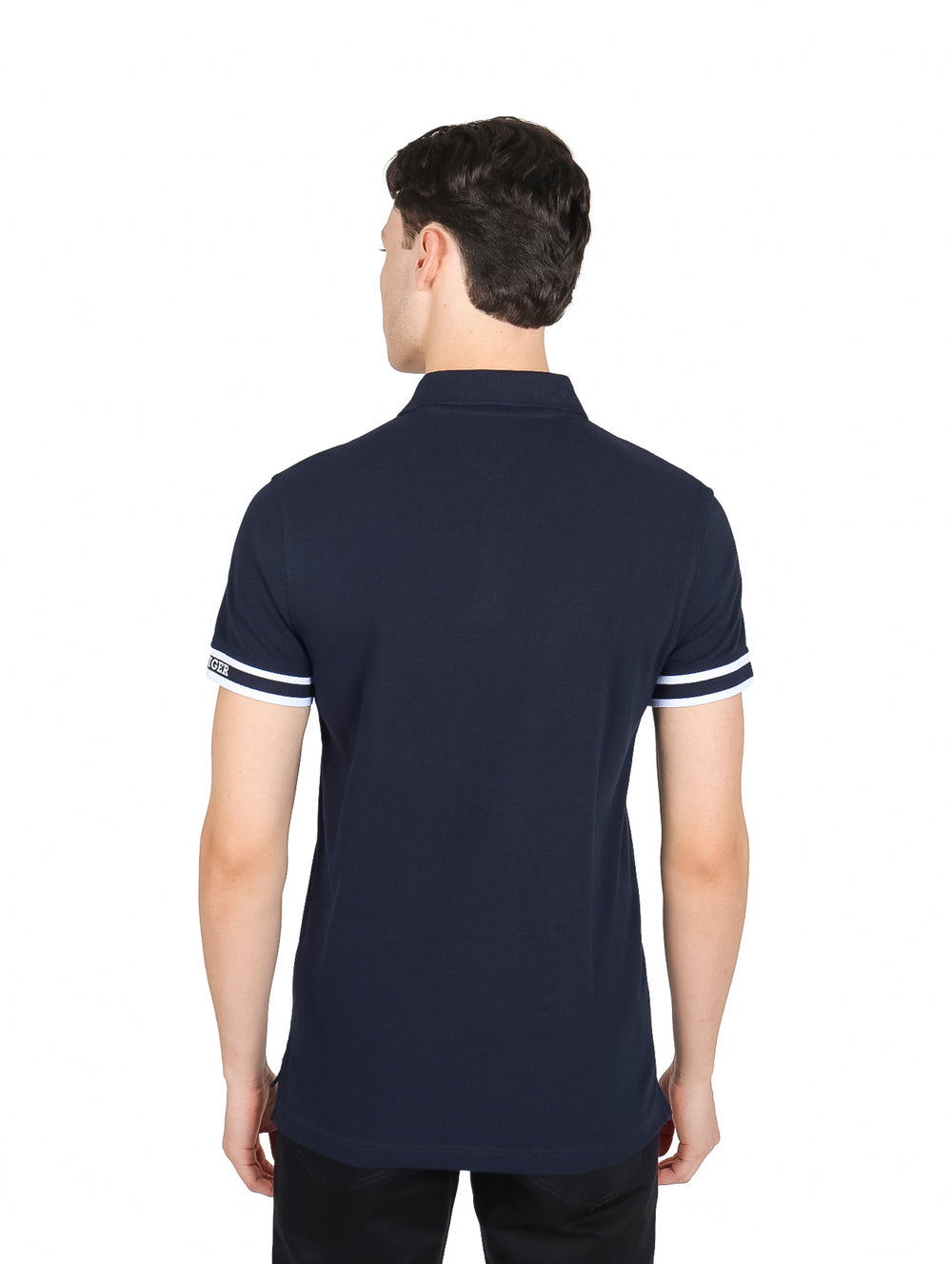 Hombre vistiendo polo Tommy Hilfiger color azul marino con franjas blancas en los puños.