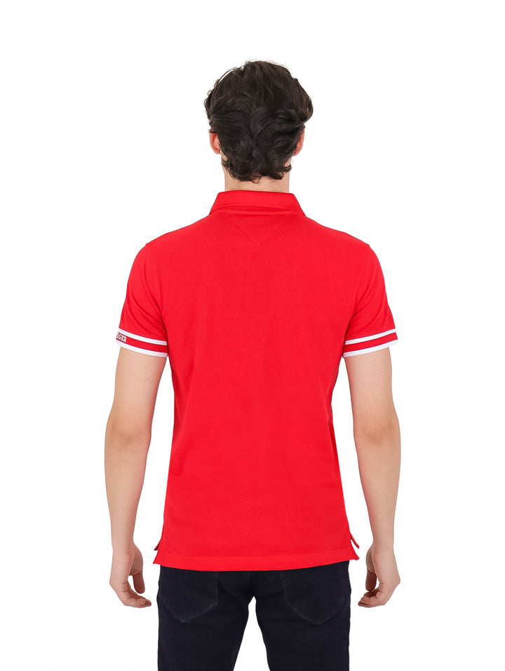 Hombre vistiendo polo Tommy Hilfiger color rojo con rayas blancas en el cuello y puños.