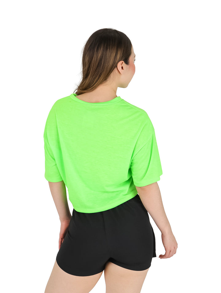 Mujer vistiendo una blusa lisa de color verde neón con mangas cortas y cuello redondo.