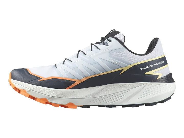 Tenis Salomon Thundercross color blanco y gris con detalles en naranja y suela para trail.