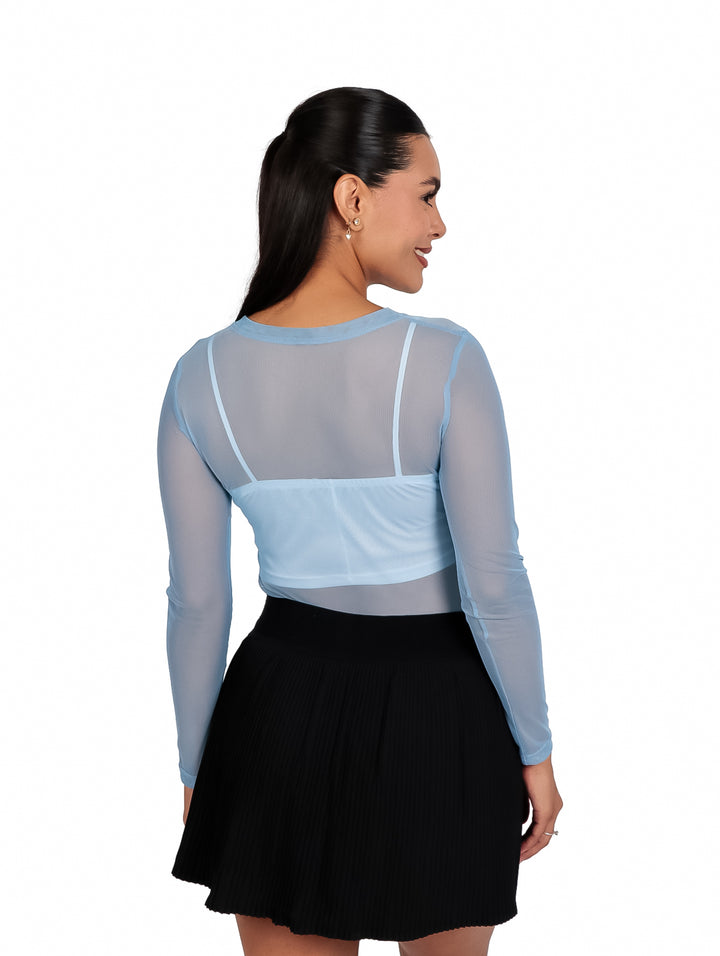 Mujer vistiendo blusa mesh de manga larga en color azul cielo y falda negra plisada.