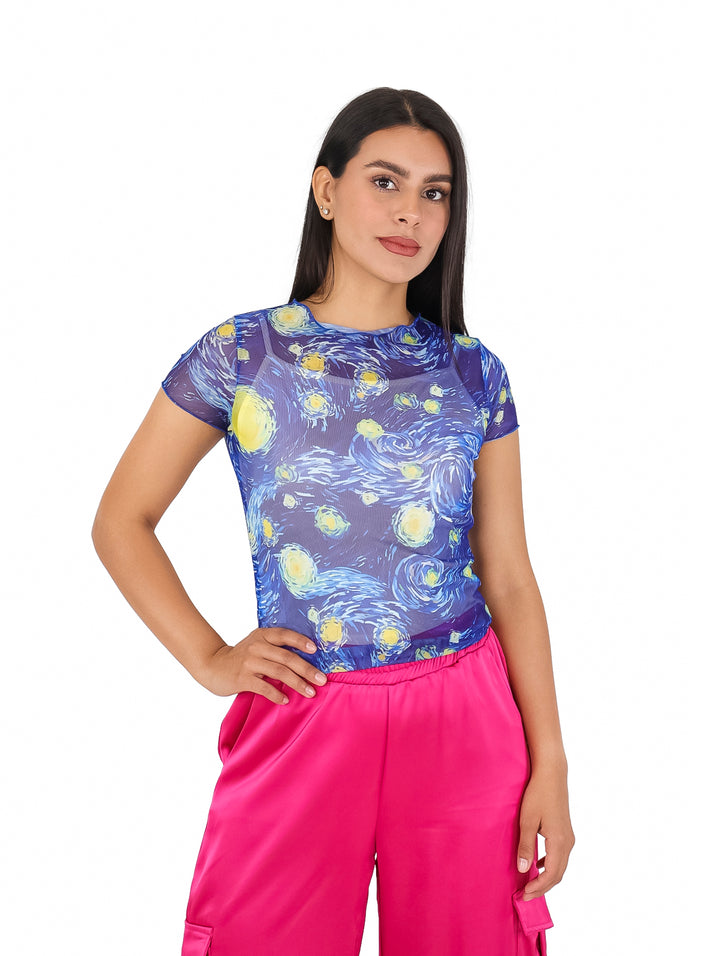 Mujer vistiendo blusa azul de tela mesh con estampado de cielo estrellado y pantalones rosas.