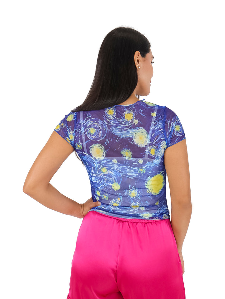Mujer vistiendo blusa azul de tela mesh con estampado de cielo estrellado y pantalones rosas.