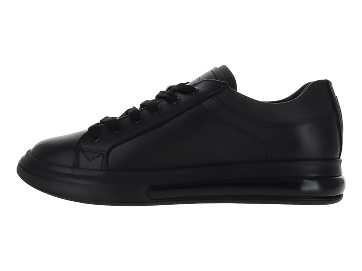 Zapato casual tipo tenis en color negro sólido con agujetas y suela negra.