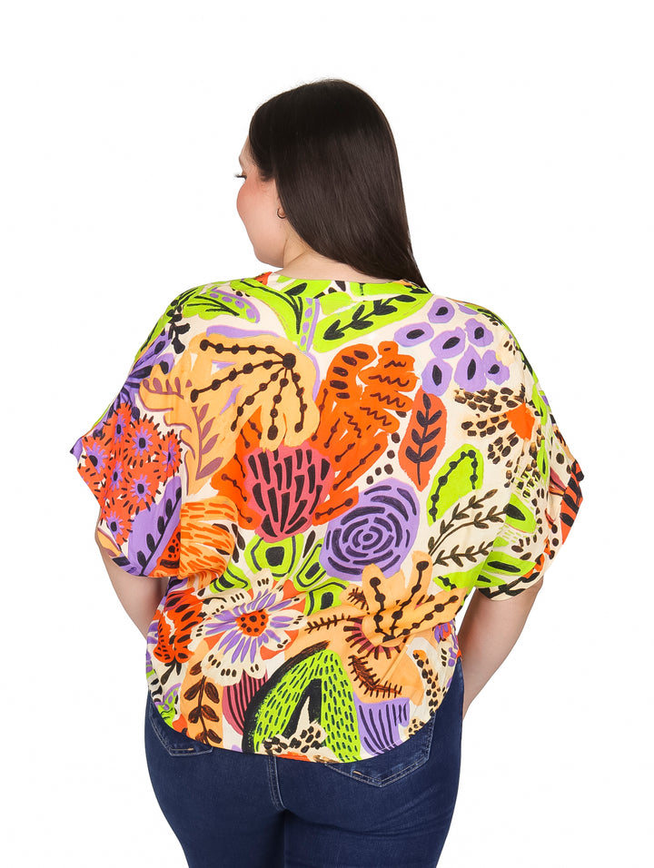Mujer vistiendo blusa multicolor estampada de manga corta y cuello en V.