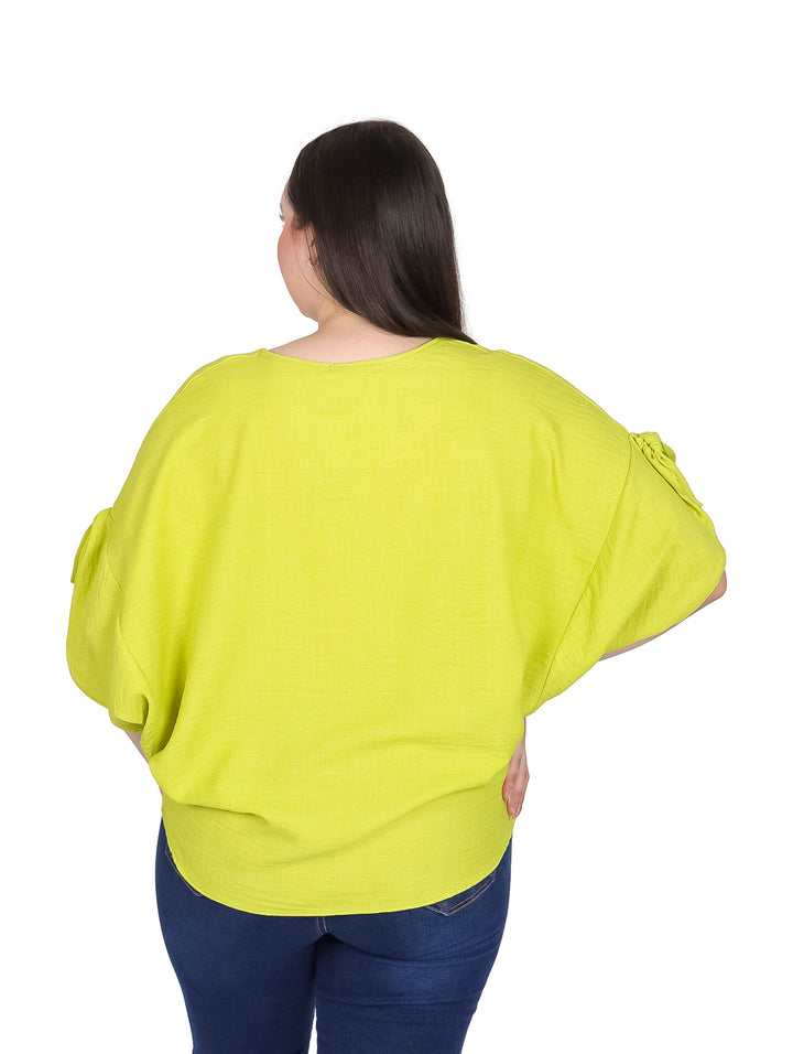 Mujer vistiendo una blusa color lima de corte curvy con cuello en V y detalles en las mangas.
