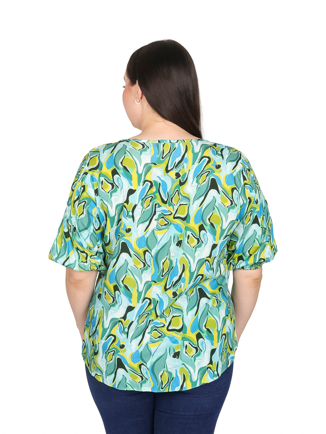 Mujer vistiendo blusa de manga corta con estampado abstracto en tonos menta, azul y amarillo.
