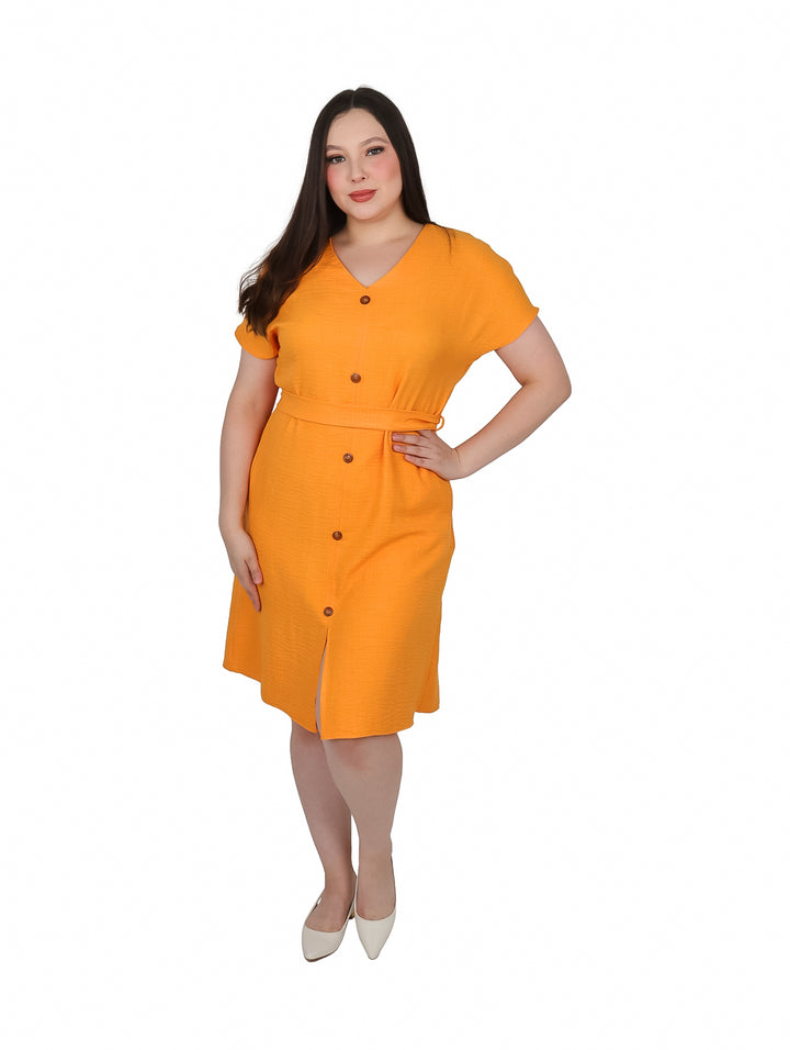 Mujer vistiendo un vestido camisero color mango con botones frontales y amarre en la cintura.