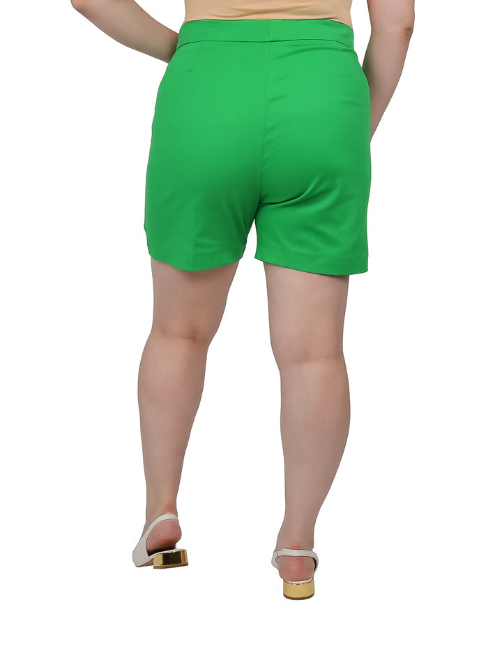 Mujer vistiendo shorts cortos de color verde brillante con cintura alta y bolsillos laterales.