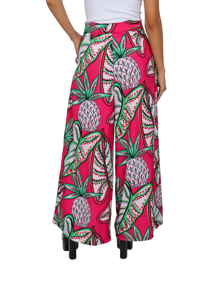 Pantalones culotte color fucsia con estampado tropical de piñas y hojas verdes.