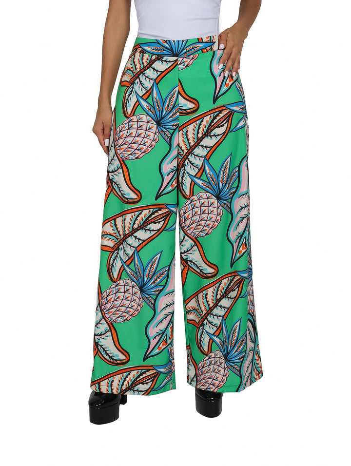 Pantalón ancho color verde con estampado tropical de piñas y hojas en tonos naranja y azul.