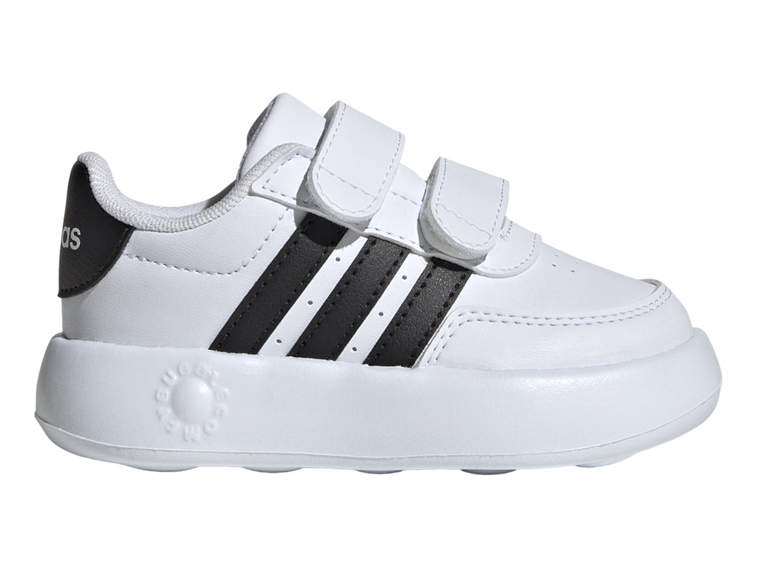 Tenis Adidas blancos para niño con tres franjas negras y cierre de velcro.