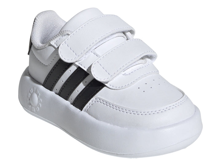 Tenis Adidas blancos para niño con tres franjas negras y cierre de velcro.