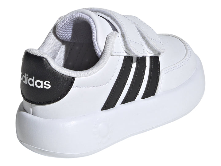 Tenis Adidas blancos para niño con tres franjas negras y cierre de velcro.