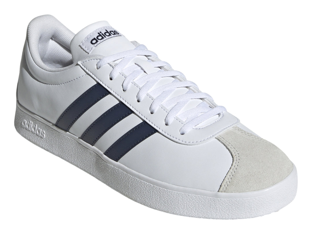 Tenis Adidas blancos con tres franjas azul marino y punta de gamuza gris.