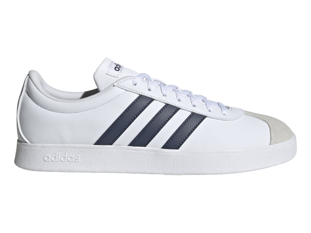 Tenis Adidas blancos con tres franjas azul marino y punta de gamuza gris.
