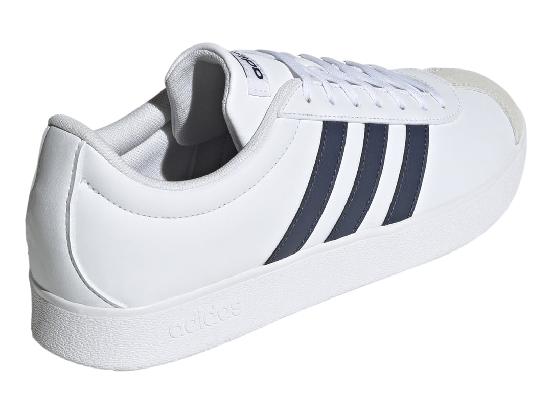 Tenis Adidas blancos con tres franjas azul marino y punta de gamuza gris.