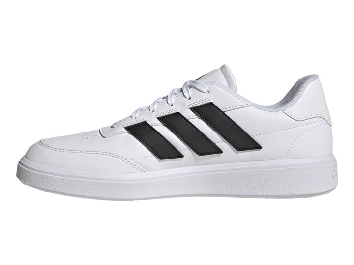 Tenis Adidas Courtblock blancos con tres franjas negras laterales y suela blanca.