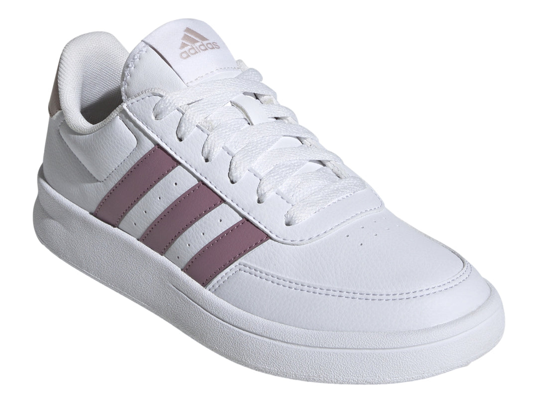Tenis Adidas blancos con tres franjas moradas y detalle beige en el talón.