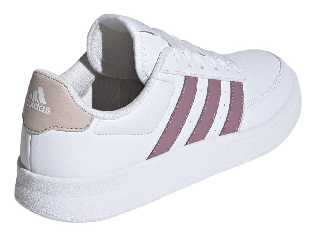 Tenis Adidas blancos con tres franjas moradas y detalle beige en el talón.