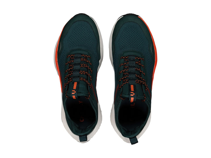 Tenis deportivos Charly color verde oscuro con detalles en naranja y suela blanca.