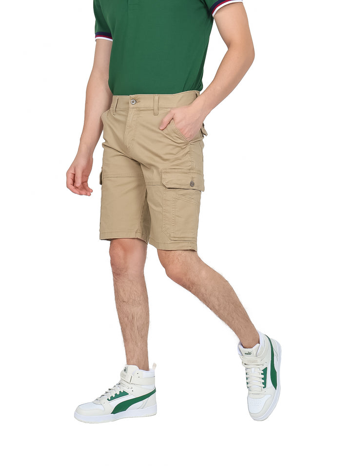 Hombre vistiendo bermudas cargo color khaki con bolsillos laterales y tenis blancos.