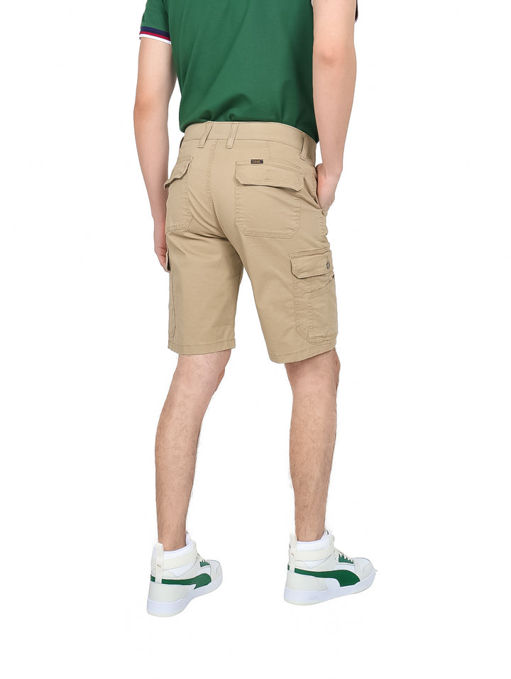 Hombre vistiendo bermudas cargo color khaki con bolsillos laterales y tenis blancos.