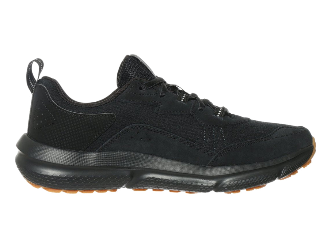 Tenis deportivo Under Armour de color negro con suela marrón, vista lateral.