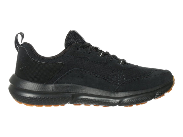 Tenis deportivo Under Armour de color negro con suela marrón, vista lateral.