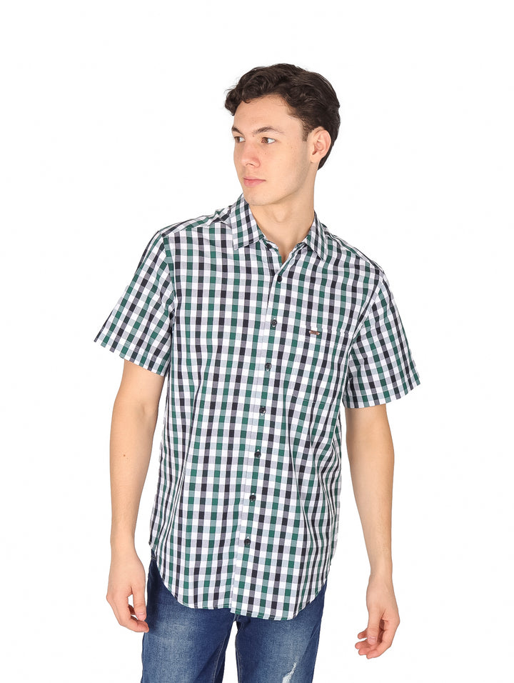 Hombre vistiendo camisa de manga corta con estampado de cuadros en colores verde, blanco y azul marino.
